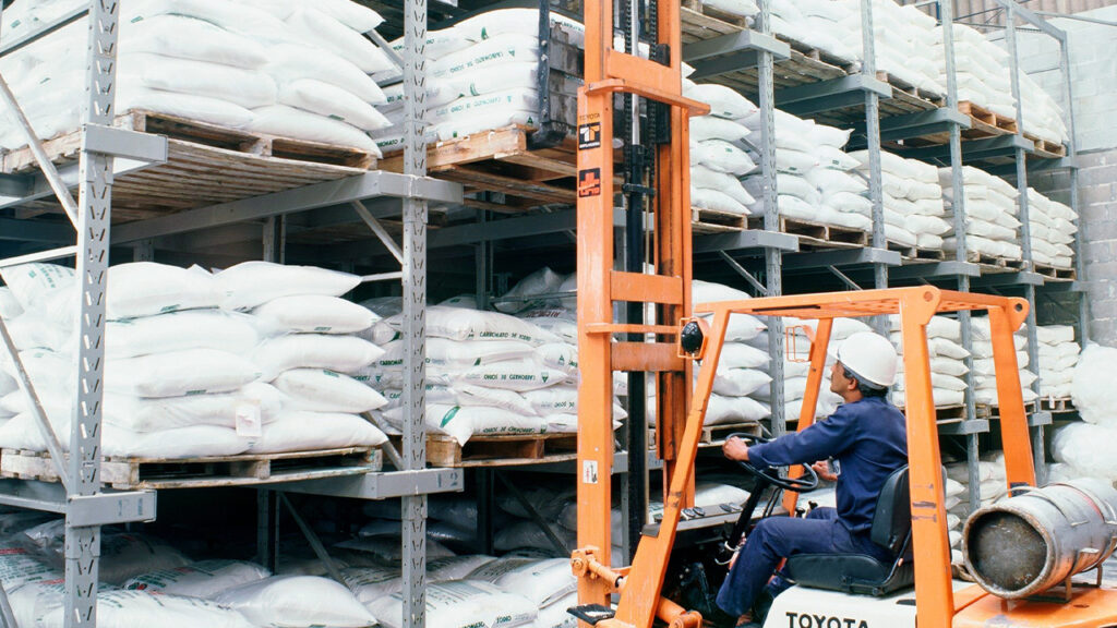 Operador realizando picking em flow rack com estrutura metálica organizada